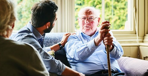 Elderly senior man sitting holding cane with family
